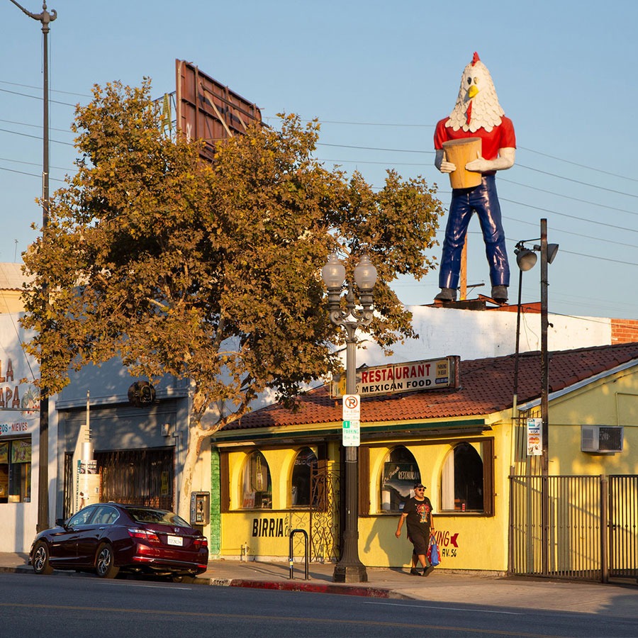 Mexican restaurant with large chicken-man statue on top in Highland Park